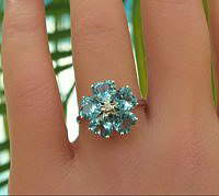 A stunning blue topaz ring with heart-shaped gemstones and a center star prong in 14k gold.
