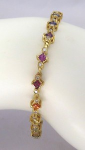 Delicate rainbow sapphire bracelet in 14k white gold featuring vibrant sapphires and diamonds.