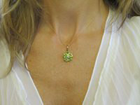 A delicate peridot flower pendant with heart-shaped stones in 14k gold.