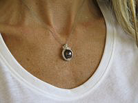 A luxurious Tahitian pearl pendant with pave diamonds, showcasing a stunning plum-colored pearl with peacock and grey overtones.