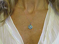 A blue topaz pendant in 14k gold with heart-shaped garnet gemstones and a diamond accent star prong.