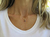 A dainty oval tanzanite pendant in 14k yellow gold with diamond accents.