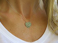 A heart-shaped pendant with pave tsavorite garnets and a diamond swirl design in 14k white gold.