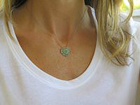 A heart-shaped pendant with pave tsavorite garnets and a diamond swirl design in 14k white gold.