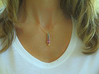 A stunning pendant featuring a large pink sapphire and vibrant rainbow sapphires in a long channel setting.