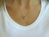 A 14k gold pendant featuring a bright 5mm round pink sapphire in a unique U-shape design setting.