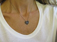 A heart-shaped pendant with blue sapphires and diamonds in black rhodium setting.