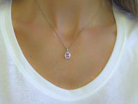 Elegant oval pink sapphire pendant necklace with diamond halo in 14k white gold.