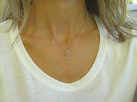Delicate pink sapphire pendant with diamond halo in 14k white gold.