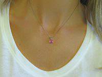 A stunning pink sapphire pendant set in 14k white gold with floral detail.