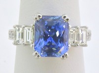 Radiant cut Ceylon sapphire ring with baguette and round diamonds in engraved 18k white gold setting.