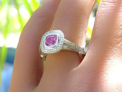 Pink sapphire and diamond halo ring in platinum with milgrain detail.