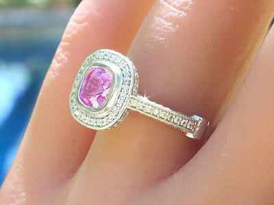 A stunning Cushion Cut Pink Sapphire and Diamond Halo Ring in Platinum with Milgrain Detail.