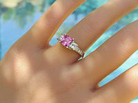 A stunning princess cut pink sapphire and diamond ring in 14k white gold, featuring a vibrant pink sapphire center stone and sparkling princess cut diamonds on a trellis style band.