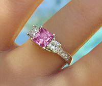 A stunning princess cut pink sapphire and diamond ring in 14k white gold, featuring sparkling diamonds on a trellis-style setting.