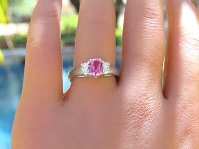 A stunning three stone ring featuring an oval pink sapphire and oval diamonds in 14k white gold.