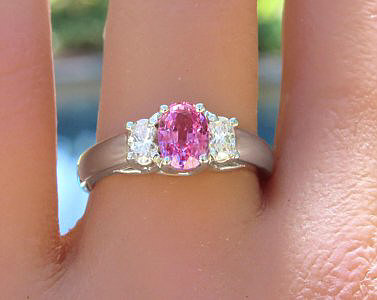 A stunning three stone ring featuring an oval pink sapphire and oval diamonds in 14k white gold.