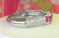 Elegant round pink sapphire ring with pave diamonds in 18k white gold, showcasing feminine sophistication and grace.