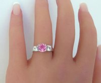 A stunning Ceylon Pink and White Sapphire Three Stone Ring in 18k white gold, symbolizing love and commitment.