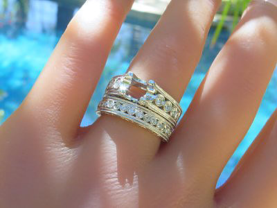 Elegantly designed round diamond engagement ring and matching band in 18k white gold, featuring bezel set diamonds and intricate milgrain detailing.
