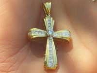 Shimmering princess cut diamond cross pendant with round diamond center in 14k yellow gold.
