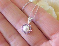 Natural pink sapphire pendant surrounded by a diamond halo, set in 14K white gold.