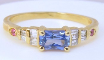 Radiant cut blue sapphire ring with pink sapphires and baguette diamonds set in 14k yellow gold.