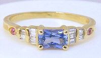 Radiant cut blue sapphire ring with pink sapphires and baguette diamonds set in 14k yellow gold.