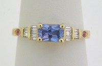 Radiant cut blue sapphire ring with pink sapphires and baguette diamonds set in 14k yellow gold.